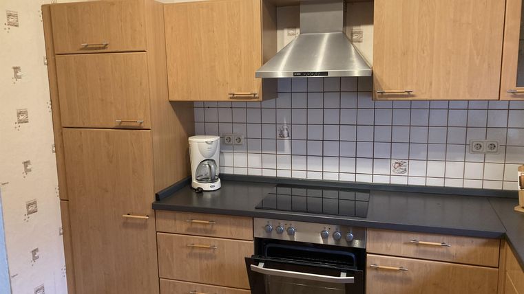 Eine moderne Küche mit Holzoptik und schwarzen Arbeitsflächen. Der Raum ist hell und freundlich gestaltet.