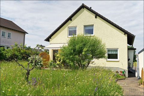 Ein gelbes Haus mit einem Garten voller Pflanzen. Die Landschaft wirkt ruhig und einladend.