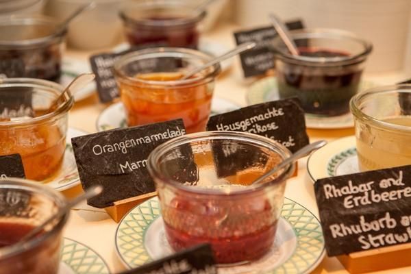 Eine Auswahl von verschiedenen Marmeladen in kleinen Gläsern. Jedes Glas ist mit einem Schild versehen, das den Geschmack angibt.