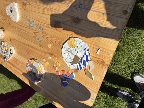 Ein Tisch aus Holz mit bunten Mosaikstücken. Einige Teile bilden runde, kreative Muster.