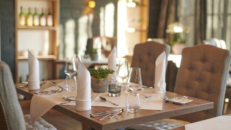 Ein stilvoll gedeckter Tisch in einem Restaurant mit eleganten Stühlen. Die Atmosphäre ist warm und einladend, mit dezenten dekorativen Elementen.