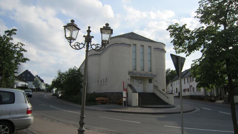 A quiet street with a church and a lantern.
Surrounded by trees and residential buildings.