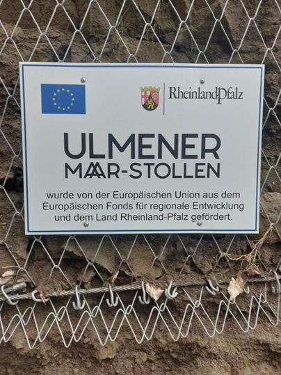Ein Schild, das den Ulmener Maar-Stollen beschreibt. Es weist auf die Förderung durch die EU und das Land Rheinland-Pfalz hin.