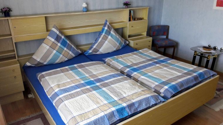Ein gemütliches Schlafzimmer mit einem Doppelbett und karierten Bettdecken. Die Möbel sind in hellem Holz gehalten und der Raum wirkt einladend.