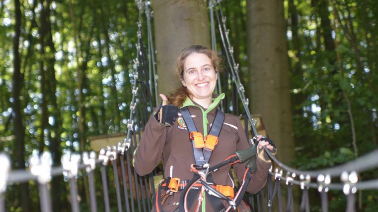 Lächelnde Frau auf Hängebrücke mit Zipline