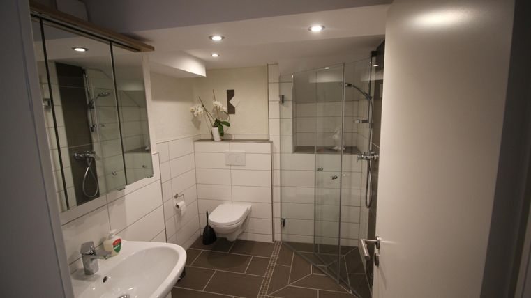 Ein modernes Badezimmer mit Glasdusche und hellen Fliesen. Die Ausstattung ist minimalistisch und sorgfältig gestaltet.