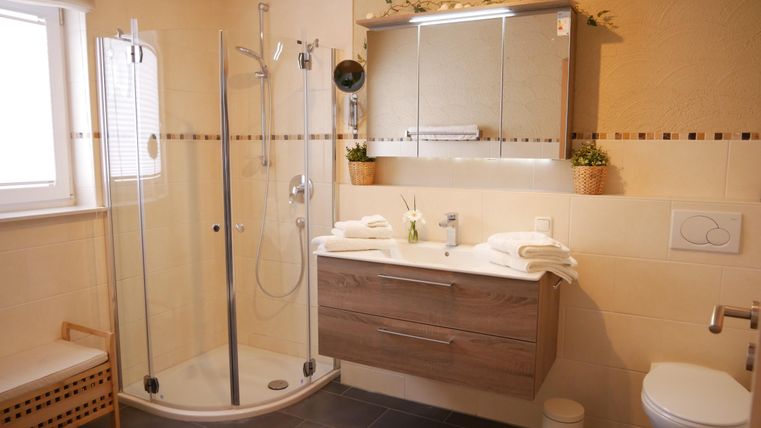 Ein modernes Badezimmer mit Dusche und Holzdesign. Es gibt große Spiegel und einen hellen, einladenden Stil.
