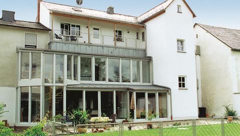 Ein modernes Haus mit großen Fenstern und einem gläsernen Anbau. Der Garten ist gepflegt und hat eine ruhige Atmosphäre.