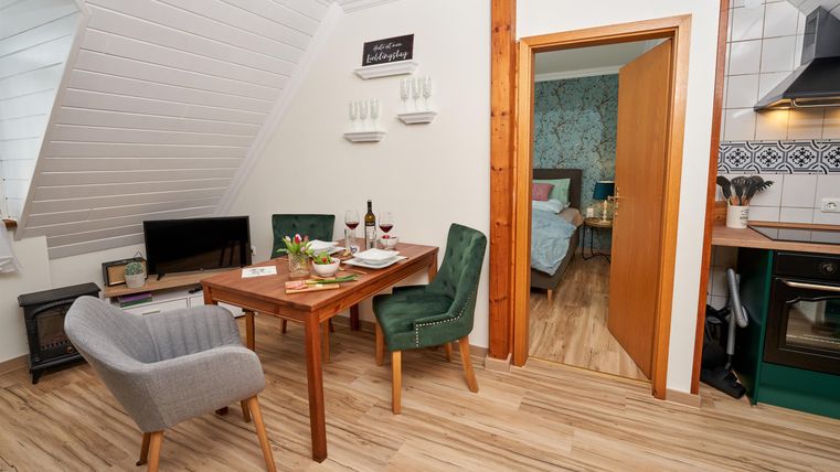 Eine gemütliche Wohnung mit einem Esstisch, zwei Stühlen und einer modernen Küche. Der Raum hat helles Holzfußboden und eine einladende Atmosphäre.