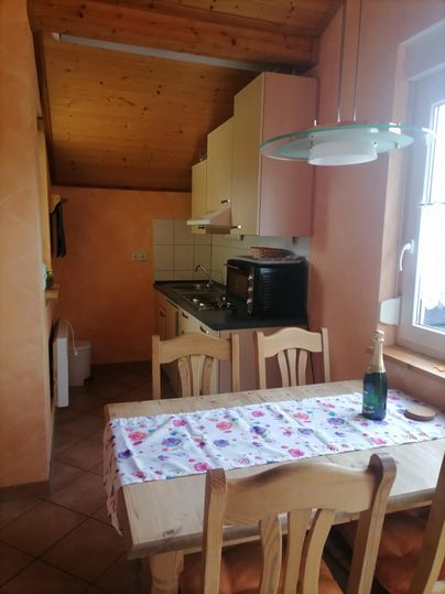 Eine gemütliche Küche mit Holzdecken und hellen Wänden. Ein Essbereich mit einem Tisch und Stühlen steht im Vordergrund.