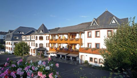 Ein charmantes Hotel mit mehreren Etagen und schönen Balkonen. Die Umgebung ist grün und gepflegt, ideal für einen entspannten Aufenthalt.