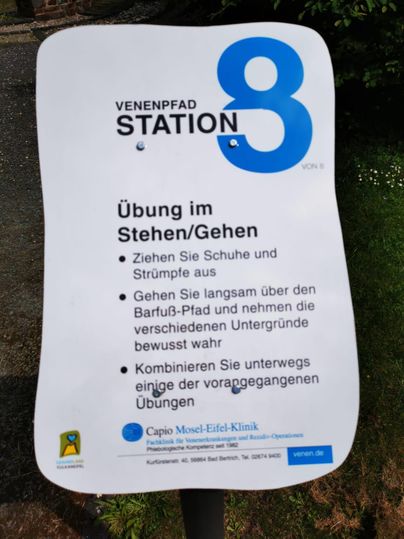 Ein Informationsschild für Station 8 des Venenpfades. Es beschreibt Übungen im Stehen und Gehen auf unterschiedlichen Untergründen.