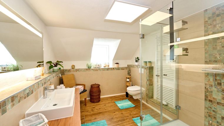 Ein modernes Badezimmer mit einer großen Dusche und einem Waschbecken. Der Raum hat helle Wände und eine elegante Holzfußboden.