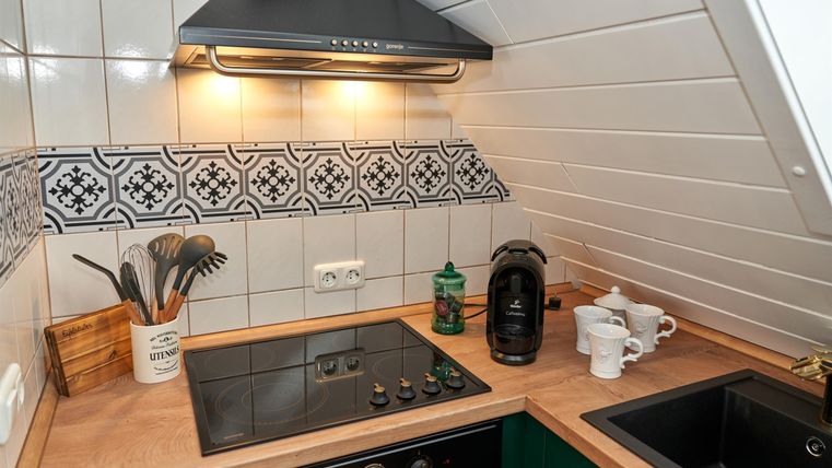 Eine moderne Küche mit einem Holzarbeitsplatz und einer eleganten Fliesenrückwand. Es gibt einen Kochfeld, eine Kaffeemaschine und Küchenutensilien auf der Arbeitsfläche.