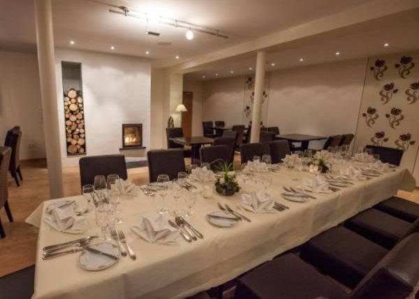 Ein eleganter Speisesaal mit einem festlich gedeckten Tisch. Im Hintergrund befindet sich ein Kamin und die Wände sind geschmackvoll dekoriert.