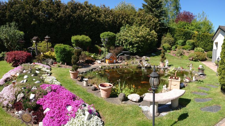 Ein schöner Garten mit bunten Blumen und einem kleinen Teich. Unsere Gartenlandschaft ist ideal für Entspannung und Naturgenuss.