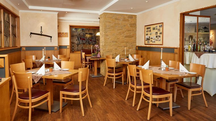 Ein gemütliches Restaurant mit Holztischen und Stühlen. Die Atmosphäre ist freundlich und einladend, ideal für ein entspanntes Essen.