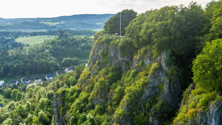 Luftaufnahme der Munterley Felsen bei Gerolstein mit bewaldeten Klippen und Häusern im Tal.