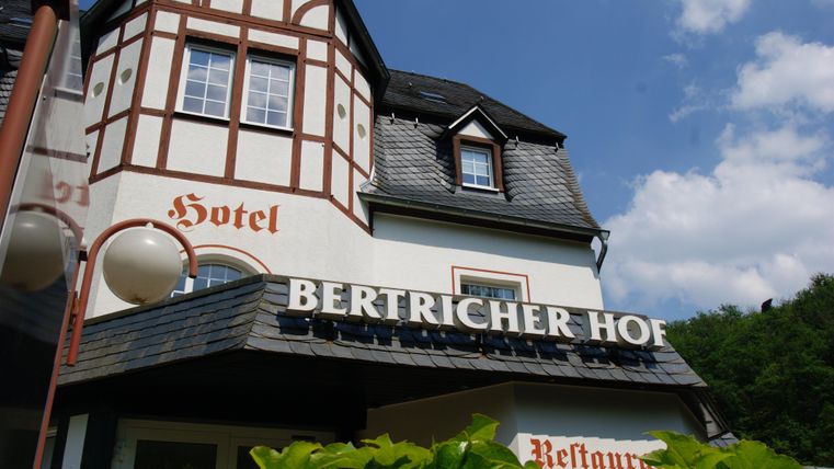 Ein charmantes Hotel mit traditioneller Architektur und einem einladenden Schild. Es befindet sich in einer grünen Umgebung.