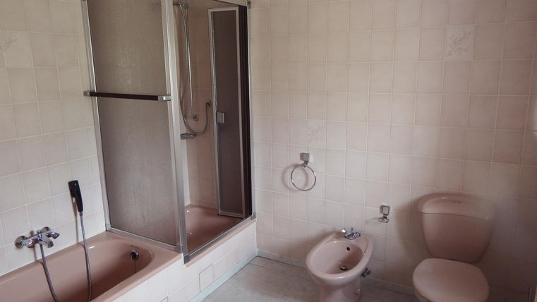 Ein schlichtes Badezimmer mit einer Dusche, einer Badewanne und einem Bidet. Die Wände sind hell gefliest und der Raum wirkt sauber und aufgeräumt.
