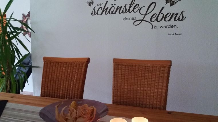 Ein einladender Esstisch mit zwei Stühlen und einer dekorativen Schale. An der Wand befindet sich ein inspirierendes Zitat.