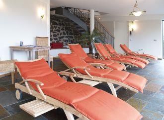 Ein entspannender Wellnessbereich mit orangefarbenen Liegen. Der Raum ist hell und freundlich gestaltet.