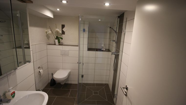 Ein modernes Badezimmer mit einer begehbaren Dusche und hellen Fliesen. Die Einrichtung ist schlicht und elegant.