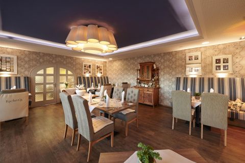 Ein elegantes Restaurant mit stilvollen Tischarrangements und gemütlichen Sitzgelegenheiten. Die warmen Farben und die dezente Beleuchtung schaffen eine einladende Atmosphäre.