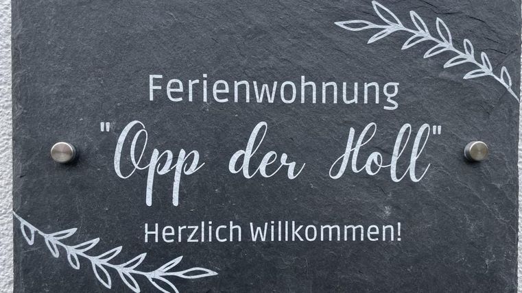 Ein Schild für eine Ferienwohnung namens "Opp der Holl". Es heißt: "Herzlich Willkommen!"