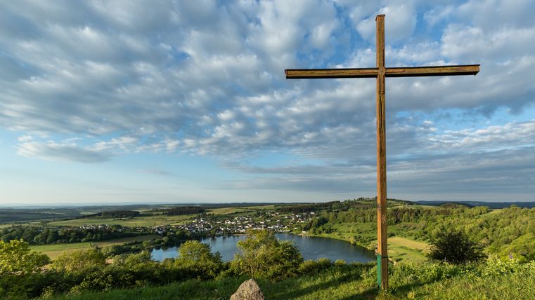Holzkreuz mit Blick auf das Schalkenmehrener Maar und die umliegende Landschaft.