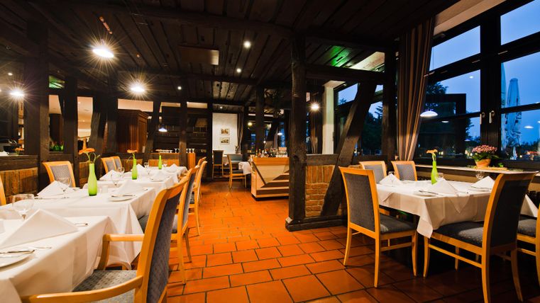 Ein stilvolles Restaurant mit eleganten Tischen und gemütlicher Beleuchtung. Die großen Fenster bieten einen Blick nach außen.