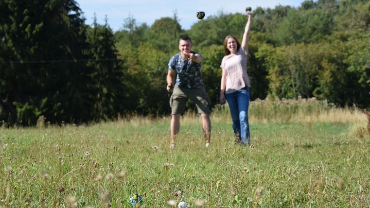 zwei Leute, die mit Bällen werfen auf einer Wiese