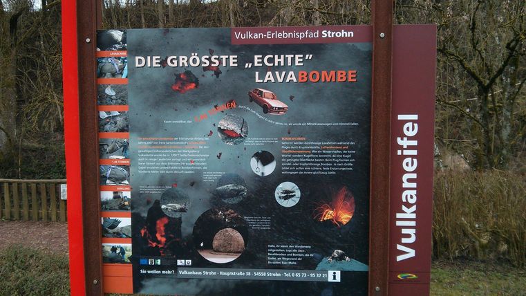 Ein Informationsschild über die größte echte Lavabombe in der Eifel. Es zeigt Bilder und Erklärungen zu Vulkanaktivität und geologischen Formationen.