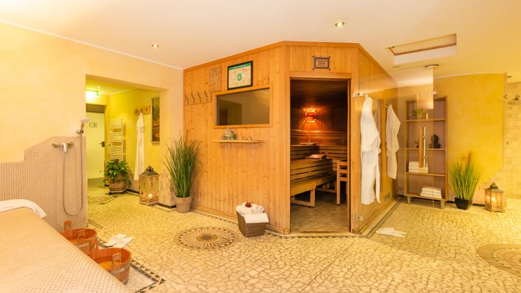 Ein ruhiger Spa-Bereich mit einer Sauna und entspannenden Elementen. Der Raum ist hell und einladend, umgeben von Pflanzen und sanfter Beleuchtung.