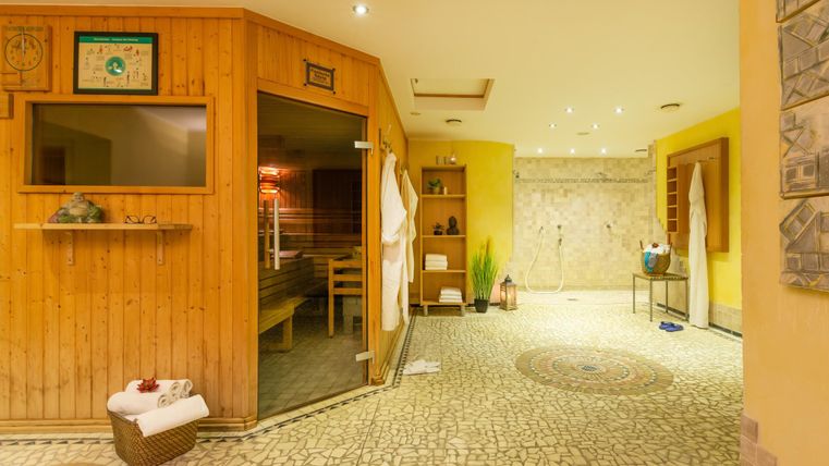 Ein gemütlicher Wellnessbereich mit einer Sauna und warmen Holztönen. Der Raum ist hell erleuchtet und hat eine entspannende Atmosphäre.