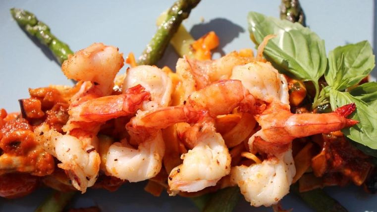 Ein köstliches Gericht mit Garnelen, grünem Spargel und frischem Basilikum. Die Zutaten sind farbenfroh angerichtet und verleihen dem Essen einen appetitlichen Eindruck.