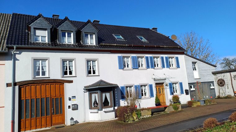 Ein schönes, zweigeschossiges Haus mit einem einladenden Eingangsbereich. Der Himmel ist klar und blau, was der Umgebung eine freundliche Atmosphäre verleiht.