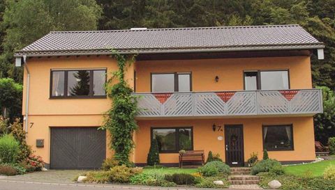 Ein modernes zweigeschossiges Haus mit orangefarbenem Außenanstrich. Der Garten ist grün und gut gepflegt, mit einer Veranda im oberen Geschoss.