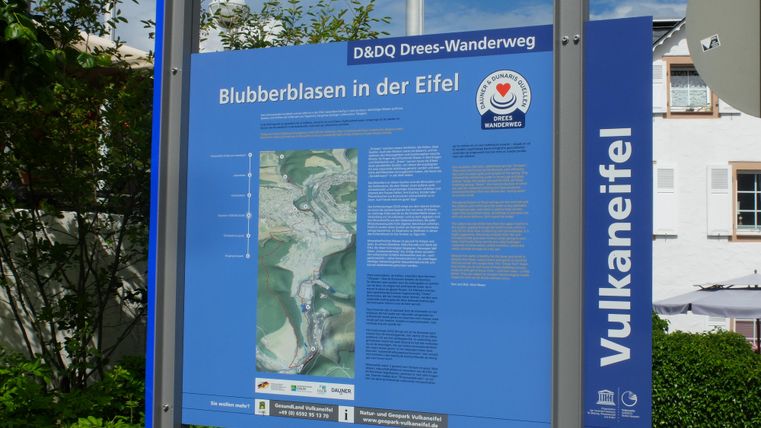 Ein Informationsschild zum Thema „Blubberblasen in der Eifel“. Es enthält eine Karte und Details zu einem Wanderweg.