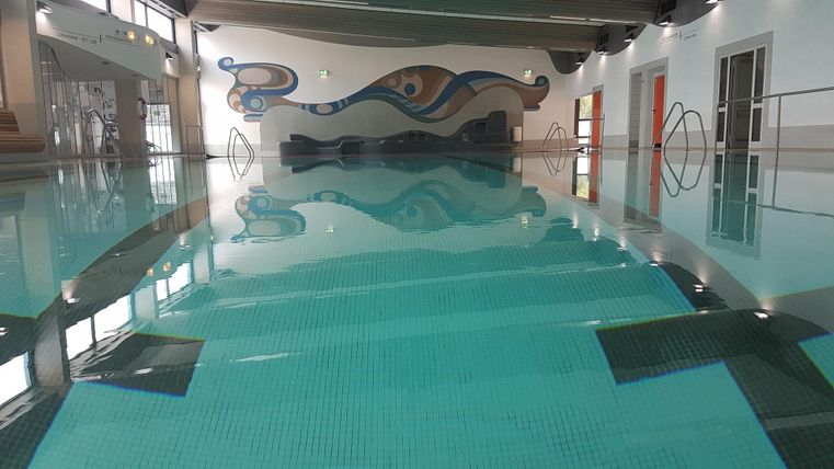 Ein modern gestalteter Pool mit klarem Wasser und einer bunten Wandmalerei. Die Umgebung wirkt einladend und ruhig.
