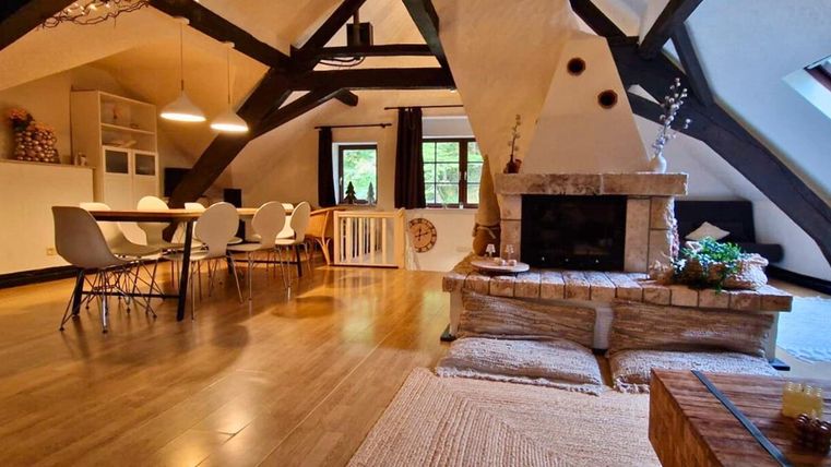 Ein modernes und stilvolles Wohnzimmer mit Holzbalken und einem gemütlichen Kamin. Der Raum ist hell erleuchtet und hat eine einladende Essbereich mit einem großen Tisch.