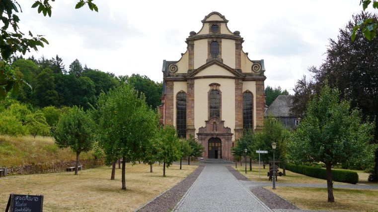 Een indrukwekkende kerk staat aan het einde van een geplaveid pad. Omringd door bomen en groenvoorzieningen straalt ze een rustige sfeer uit.