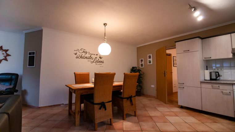 Ein helles Esszimmer mit einem großen Tisch und Stühlen. Die Wände sind in neutralen Farben gehalten, und die Küche grenzt an den Wohnbereich.