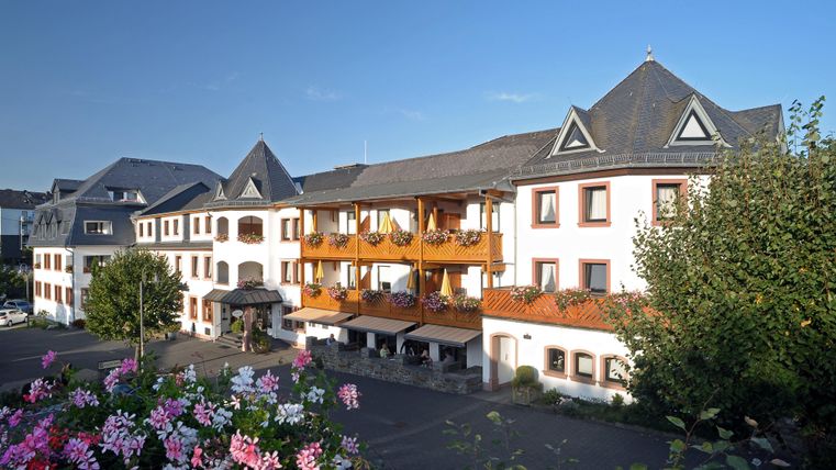 Ein charmantes Hotel mit mehreren Etagen und schönen Balkonen. Die Umgebung ist grün und gepflegt, ideal für einen entspannten Aufenthalt.
