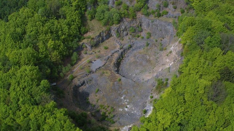 Blick von oben in den Krater des Arensberg, welcher von Wald umgeben ist.