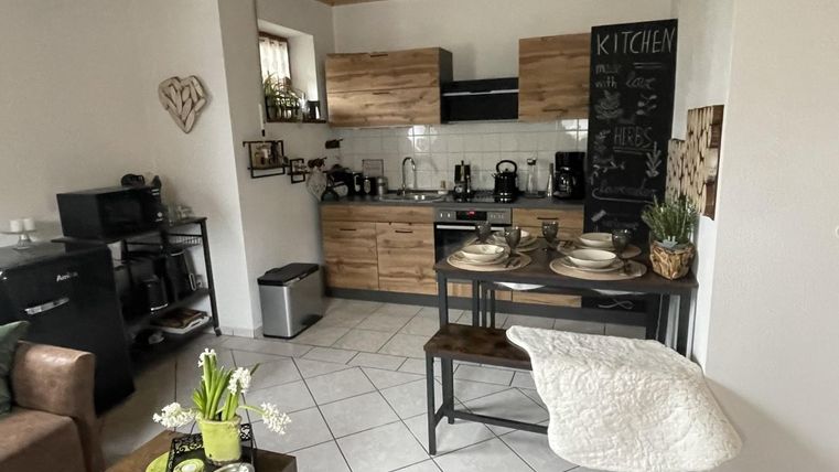 Eine moderne Küche mit Holzschränken und einer kleinen Essecke. Der Raum ist hell und gemütlich gestaltet.