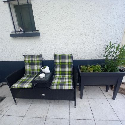 A cozy seating area with two armchairs and a small table. Next to the sofa is a plant box with green plants.