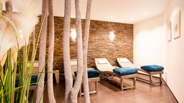 Ein ruhiger Wellnessbereich mit Liegen und modernen Holzelementen. Sanftes Licht und eine angenehme Atmosphäre laden zur Entspannung ein.