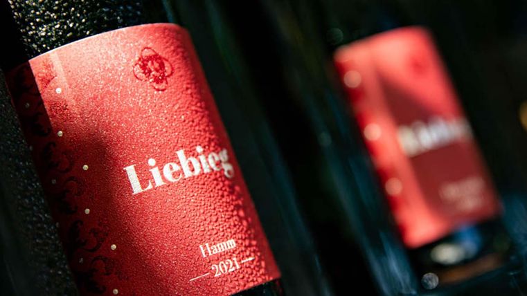 Ein Bild von Flaschen mit rotem Etikett, die den Namen "Lieblich" tragen. Die Flaschen stehen in einer Reihe und scheinen im Sonnenlicht zu glänzen.