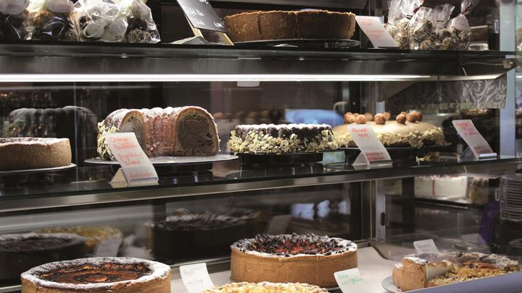 Eine Vitrine mit verschiedenen köstlichen Kuchen und Torten. Die Auswahl umfasst Schokoladenkuchen, Käsekuchen und Obsttorten.